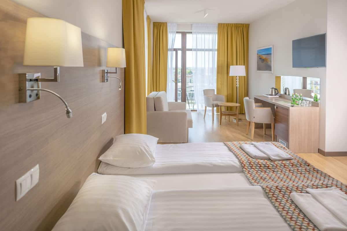 A hotel room with a bed, a desk, a chair, and a view of the city.