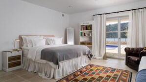 A bedroom with a bed, nightstand, bookshelf, and a view of a pool through a glass door. - Exclusive and private Villa, seaside in Vinisce, 30 min from Split airport (Vinišće)