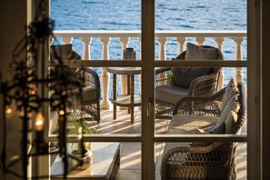 Een balkon met rieten meubilair en uitzicht op zee.