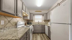 Una cocina compacta con un refrigerador blanco, una estufa y un microondas.