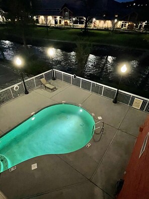 Una piscina con bordo curvo, circondata da una ringhiera bianca e affaccio su un edificio sullo sfondo.
