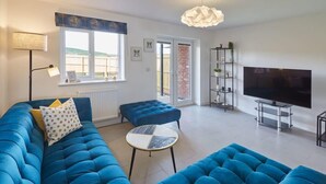 A living room with a blue sofa, a small round table, a TV, and a bookshelf.