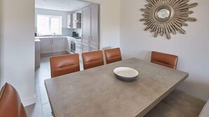 A dining area with a large table, four chairs, and a decorative wall piece.