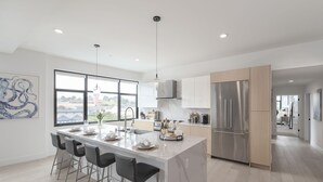 Una cocina moderna con una isla grande, electrodomésticos de acero inoxidable y vistas a la ciudad.