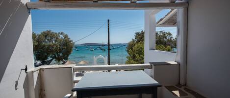 A balcony with a view of the sea and boats, a table, and a chair.