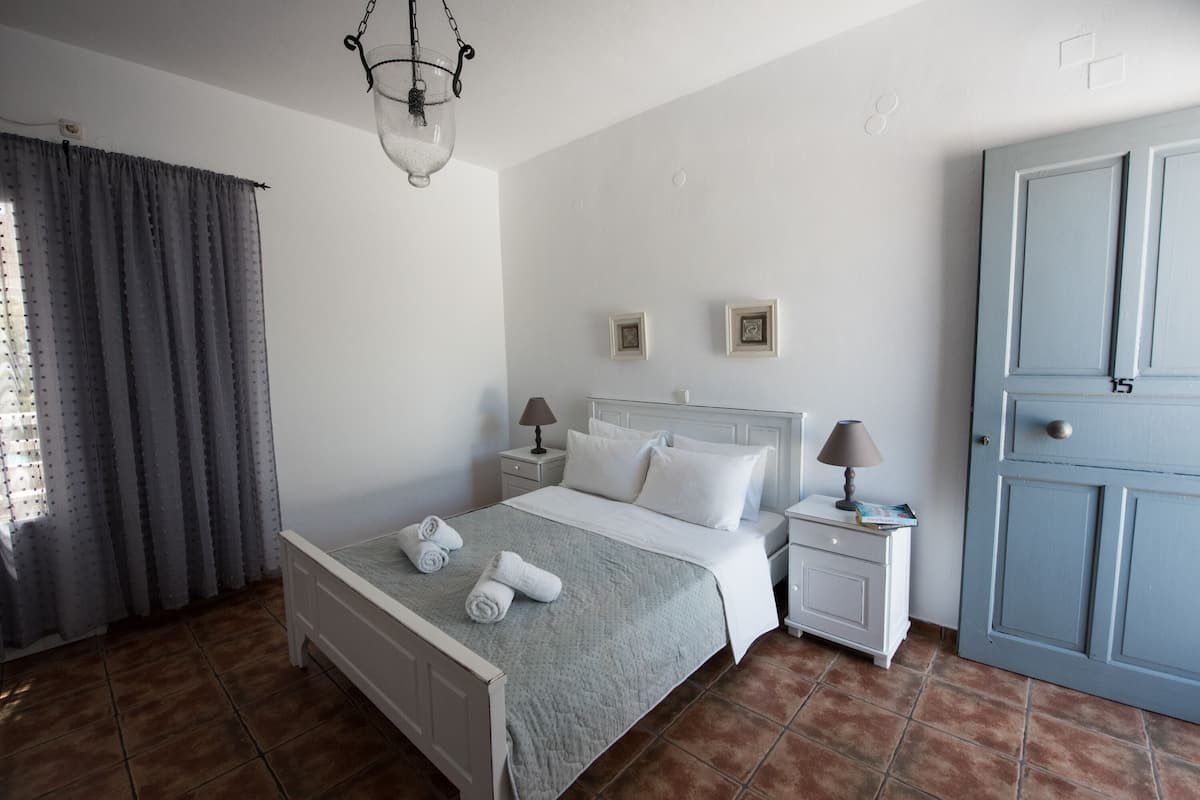 A bedroom with a bed, nightstands, a door, and curtains.