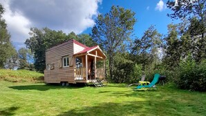 A small wooden cabin with a porch, surrounded by a grassy yard and trees. - Nuit Insolite en Tiny House (BEULOTTE SAINT LAURENT)
