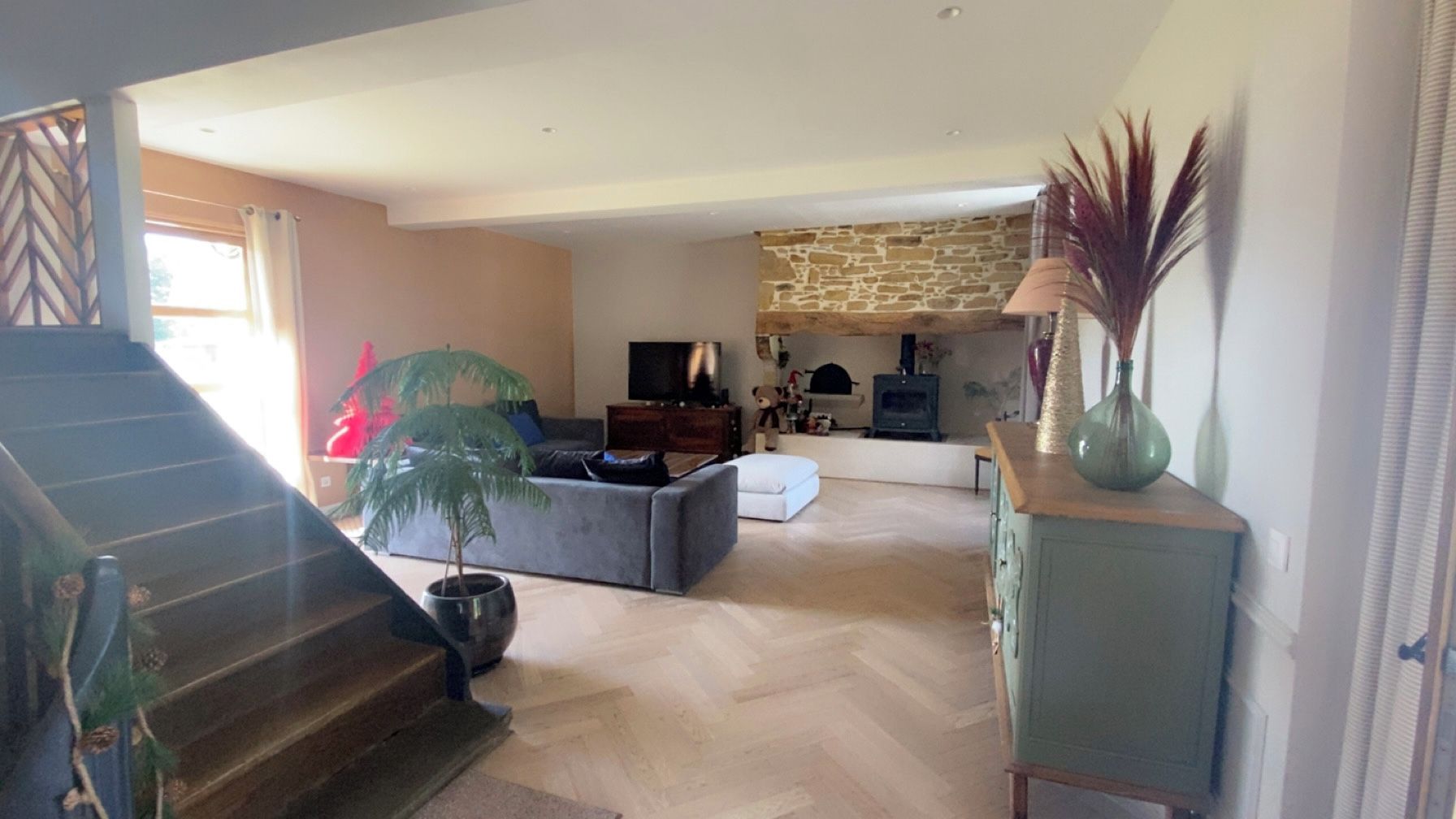 A spacious living area with a sofa, a fireplace, and a staircase leading to another level.