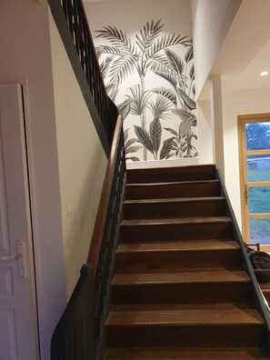 A staircase with wooden steps and a black handrail, leading to a room with a white door and a window with a view of a blue sky and greenery. - Peaceful house in the heart of the Pyrenees (Igon)