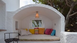 A cozy nook with a cushioned bench, a small table, and a window overlooking greenery. - Villa with private pool very close to the beach.Capacity 8 people. Wifi. (pals)