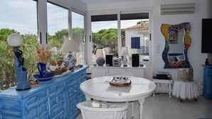 A room with a white table, blue cabinetry, and a view of greenery and buildings outside. - Villa with private pool very close to the beach.Capacity 8 people. Wifi. (pals)