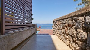 Ein Weg führt zu einem Pool mit einer Steinmauer und Holzlatten an einer Seite.