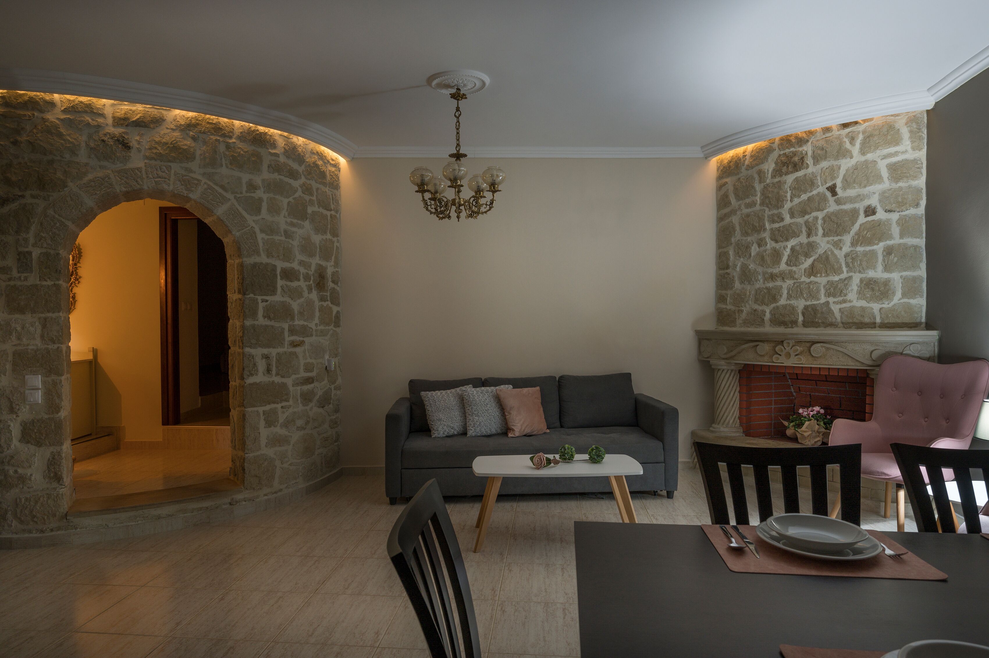 A living room with a stone wall, a fireplace, a sofa, and a dining table with chairs.