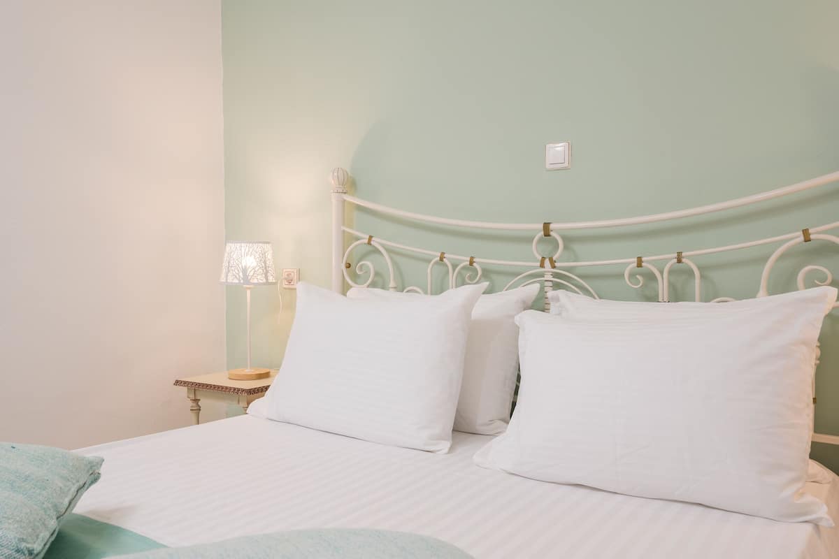 A bed with white bedding and a metal headboard in a room with light green walls.
