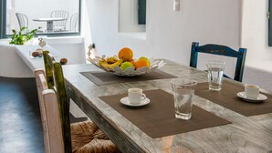 Een eettafel met een fruitschaal, twee kopjes en twee glazen.