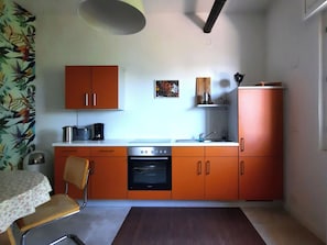 Una cocina compacta con armarios naranjas, una estufa y un lavabo.