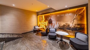 A spa area with a marble floor, seating, and a wall with a water feature and spa branding. - Amon Hotel Belek - All Inclusive (Serik)