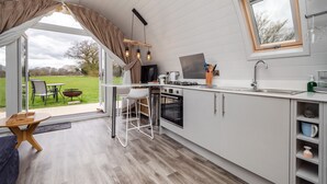Une cuisine moderne dotée d’une grande fenêtre, un coin repas avec une table et des chaises, et une vue sur une pelouse verdoyante.