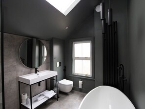 A modern bathroom with a skylight, a white sink, a toilet, and a bathtub. - Stunning, Brand New 3BR Home - Central Oxford - Pass the Keys (Oxford)