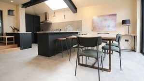 A modern kitchen with a central island, bar stools, and a dining table with chairs. - Stunning, Brand New 3BR Home - Central Oxford - Pass the Keys (Oxford)