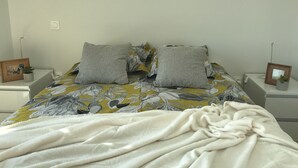 A neatly made bed with a floral bedspread, two pillows, and a white blanket. - THE LAVOISIER TERRACE (La Rochelle)