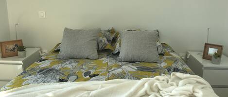 A neatly made bed with a floral bedspread, two pillows, and a white blanket.