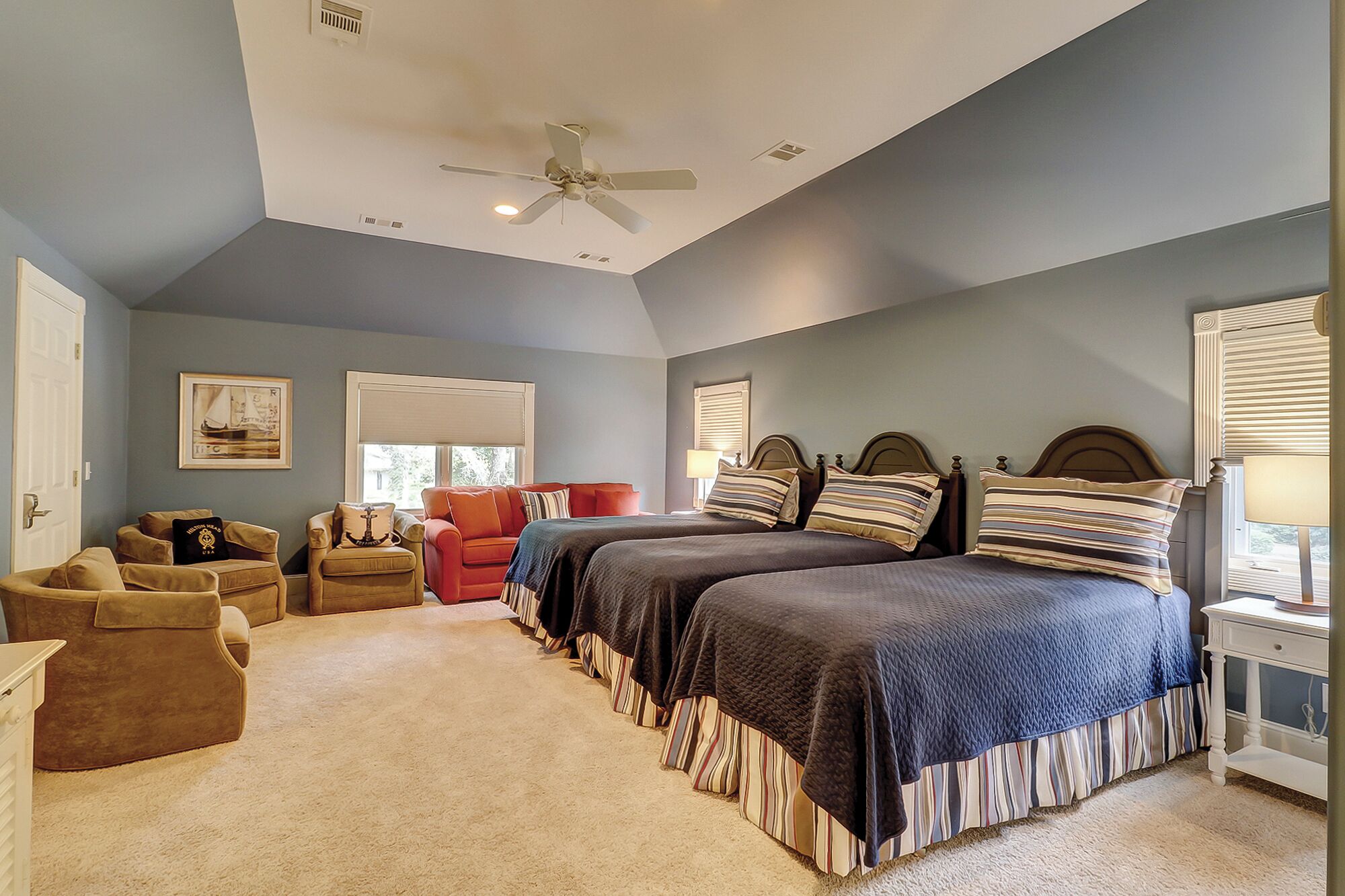 A bedroom with two beds, a ceiling fan, and a window with blinds.