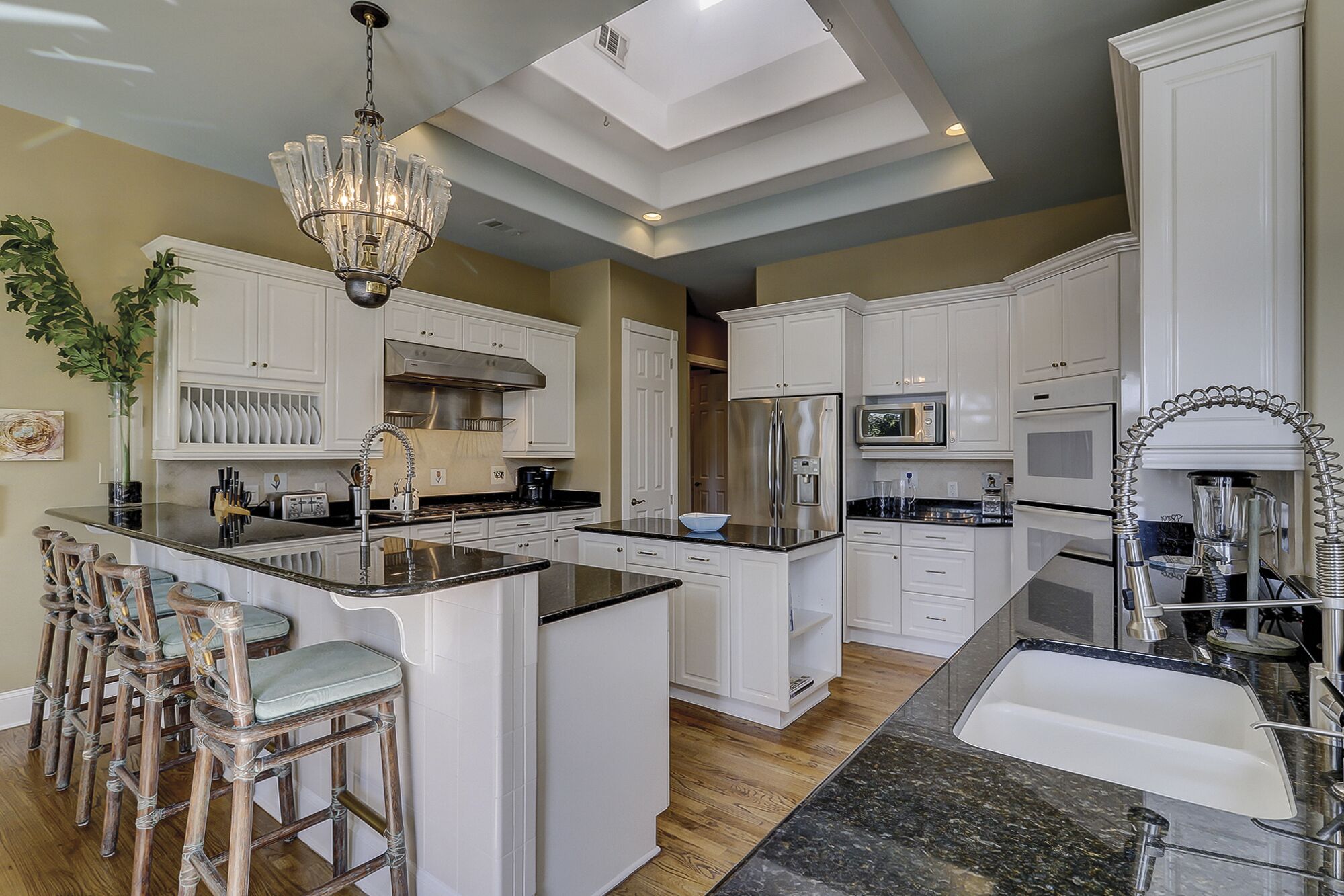 A spacious kitchen with white cabinetry, a central island, and a chandelier.