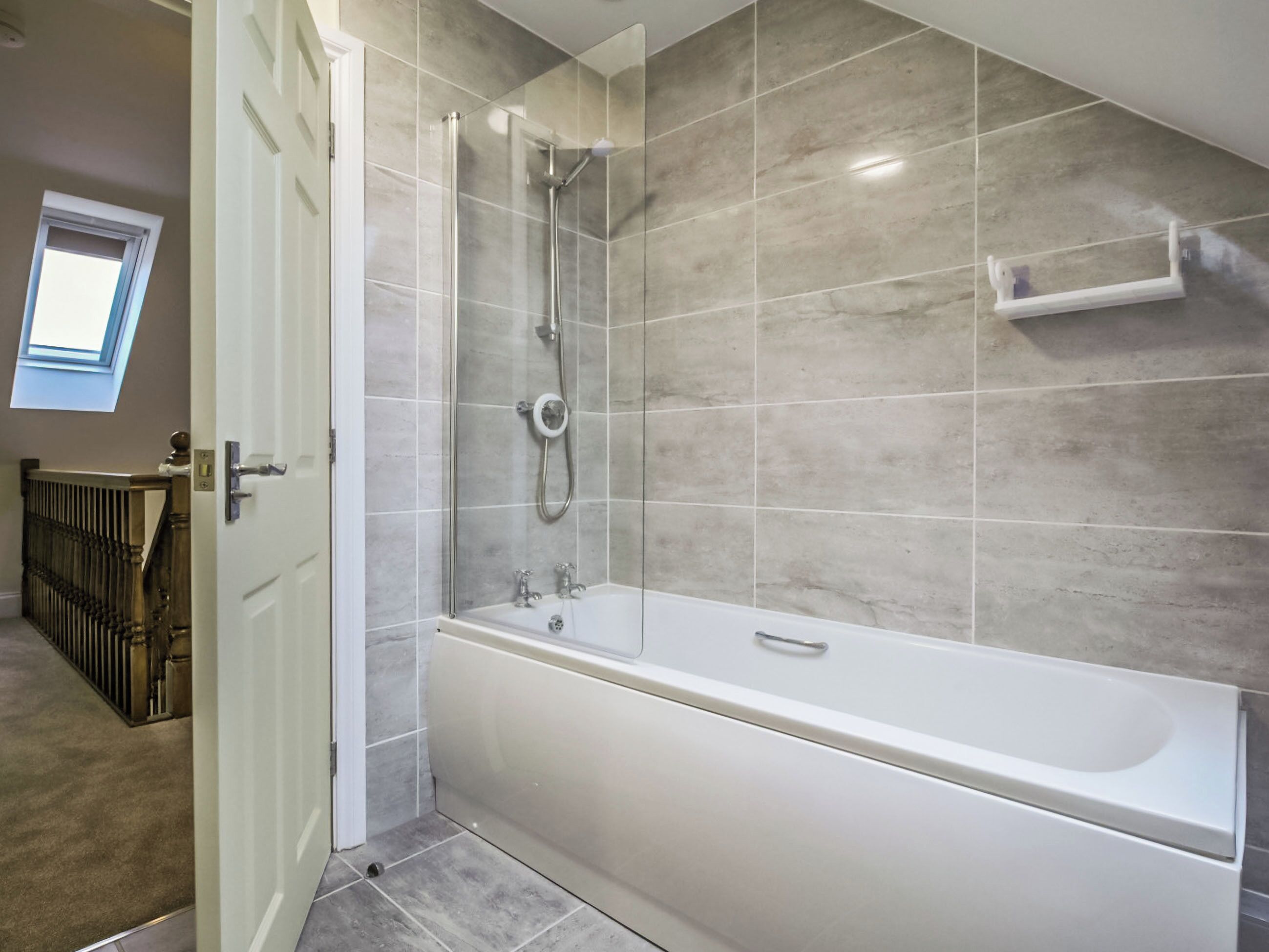 A bathroom with a bathtub, shower, and a window.