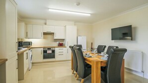 Una cocina moderna con armarios blancos, un microondas, una estufa y una mesa de comedor con sillas.