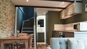 A modern kitchen with a microwave, wooden cabinets, and a staircase leading to an upper level.