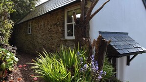 A stone house with a sloped roof and a window.