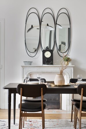 Spiseområde med et bord, stole, en vase med planter og et vægur.
