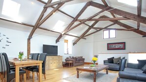 A spacious living area with wooden beams, a dining table with chairs, a sofa, a television, and a framed picture on the wall. - 3 bedroom accommodation in Butterleigh, near Tiverton (Butterleigh, near Tiverton)