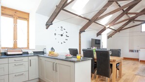 A modern kitchen with a wooden ceiling, a dining area with a table and chairs, and a wall clock. - 3 bedroom accommodation in Butterleigh, near Tiverton (Butterleigh, near Tiverton)