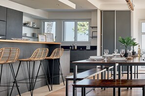 Een moderne keuken met een bar, barstoelen, een eettafel met banken en een potplant.
