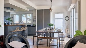 Una cocina moderna con zona de comedor, que incluye una isla central, sillas y un ventanal amplio.