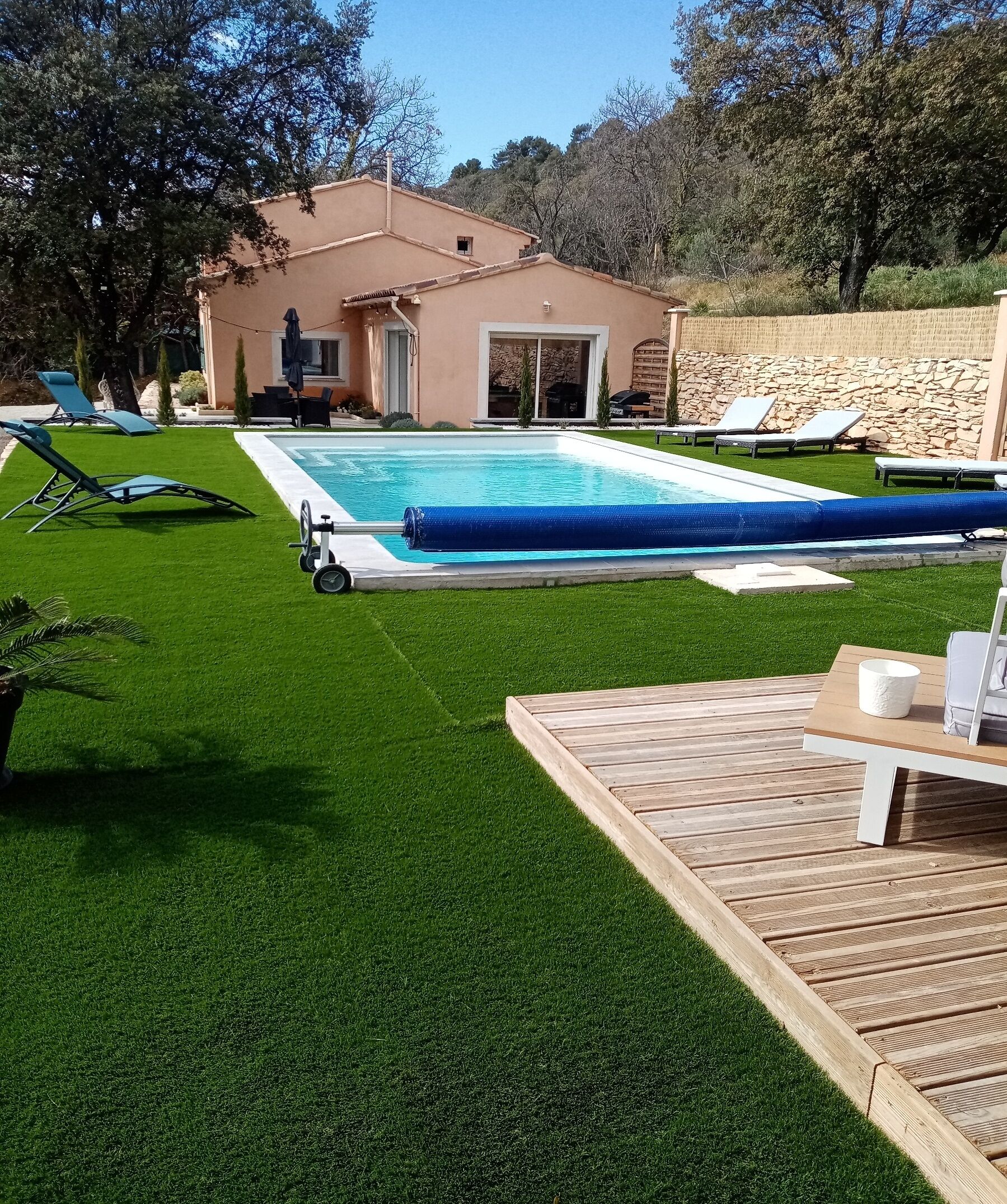 Une piscine avec une terrasse en bois et des chaises longues.