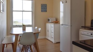 Una cocina con mesa, sillas, refrigerador, microondas y un menú en la pizarra.