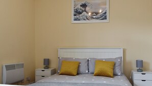 Un dormitorio con una cama, dos mesitas de noche, un cuadro en la pared y un calentador de pared.