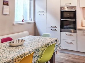 A modern kitchen with white cabinets, a built-in oven, and a window with a view. - 3 bedroom accommodation in Fortrose (Fortrose)