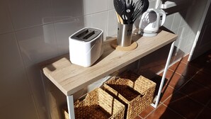 A kitchen counter with a toaster, a coffee maker, and a utensil holder. There are wicker baskets underneath the counter.