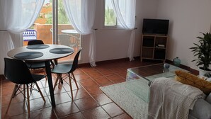 A living room with a dining area, a TV, and a balcony with a table and chairs.