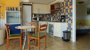 A compact kitchen with a dining area, a microwave, a coffee maker, and a trash bin. - Casa Cannobio Carmine (Carmine)