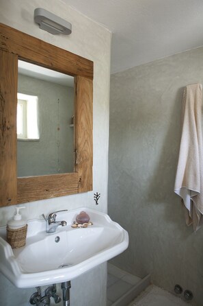 A bathroom with a wooden-framed mirror, a white sink, and a towel hanging on the wall.