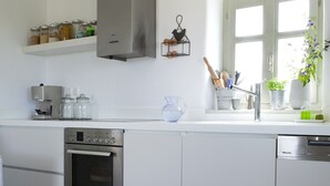 Una cucina moderna con mobili bianchi, elettrodomestici in acciaio inossidabile e un tavolo in legno.