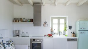Una cucina moderna con mobili bianchi, forno integrato e un frigorifero in stile vintage.