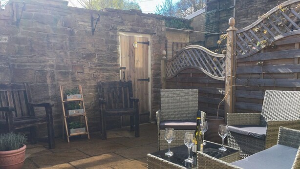 Ein Patio mit Korbmöbeln, einer Steinwand und einer Holztür.