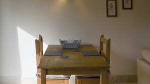 Una mesa de comedor de madera con sillas, una cesta y una lámpara fijada a la pared.