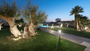 Un espace extérieur aménagé avec une piscine, des arbres et un chemin pavé.